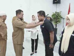 Asisten Sekda Bidang Pemerintahan dan Kesejahteraan Masyarakat DR. Syofyan Saraha Menyematkan tanda peserta kepada perwakilan peserta