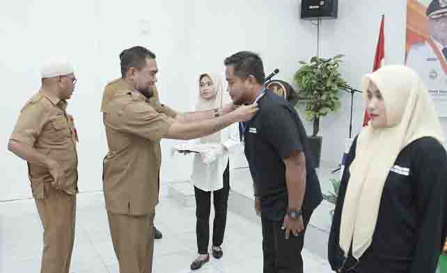 Asisten Sekda Bidang Pemerintahan dan Kesejahteraan Masyarakat DR. Syofyan Saraha Menyematkan tanda peserta kepada perwakilan peserta